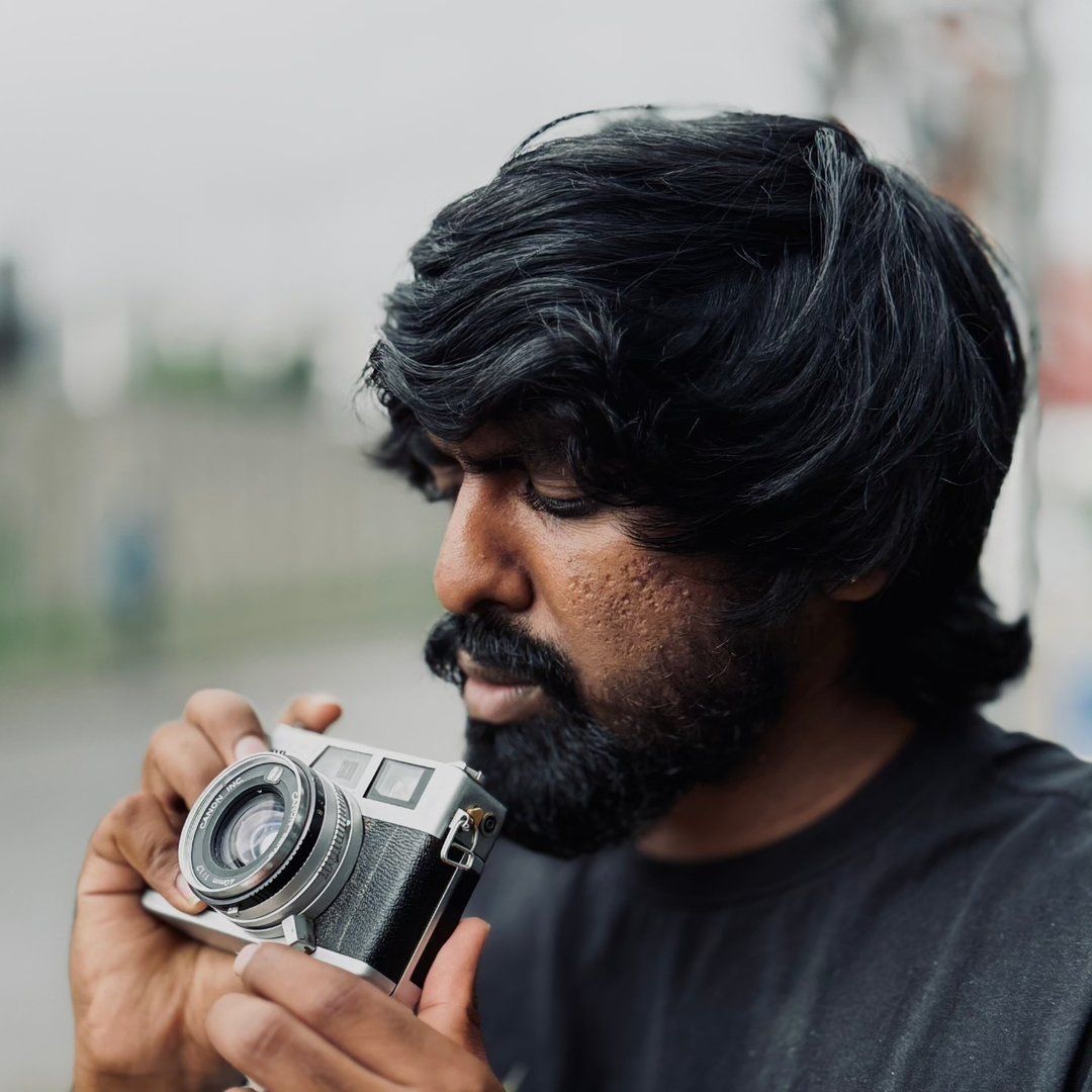 Akshay Saiju looking down at a Canon rangefinder